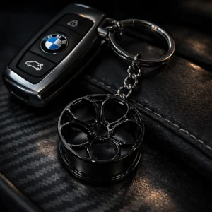 Kluczyk samochodowy BMW z brelokiem w kształcie czarnej felgi na czarnej skórzanej tapicerce